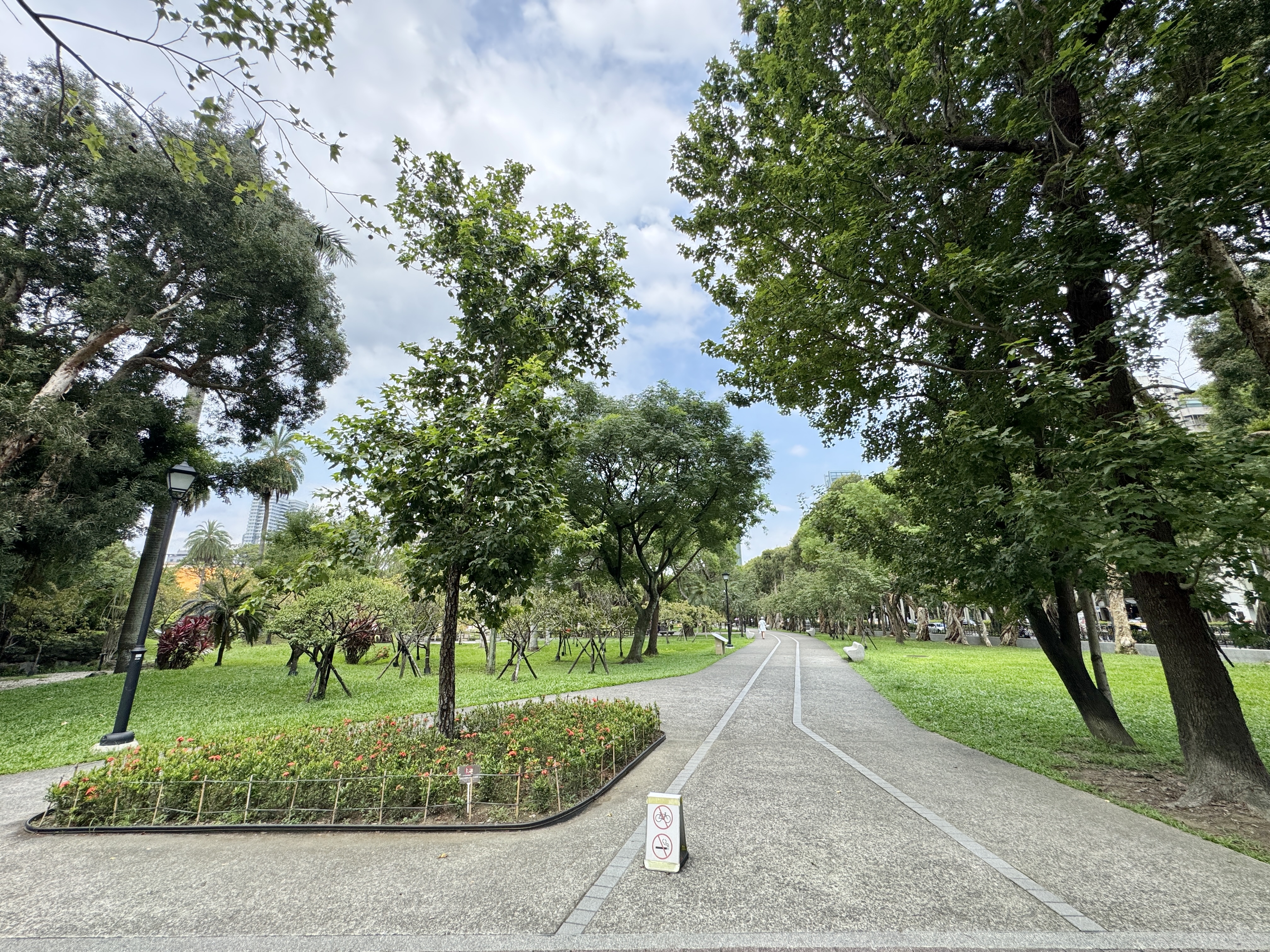 國父紀念館園區草地間的步道，兩側有樹木與開闊綠地。