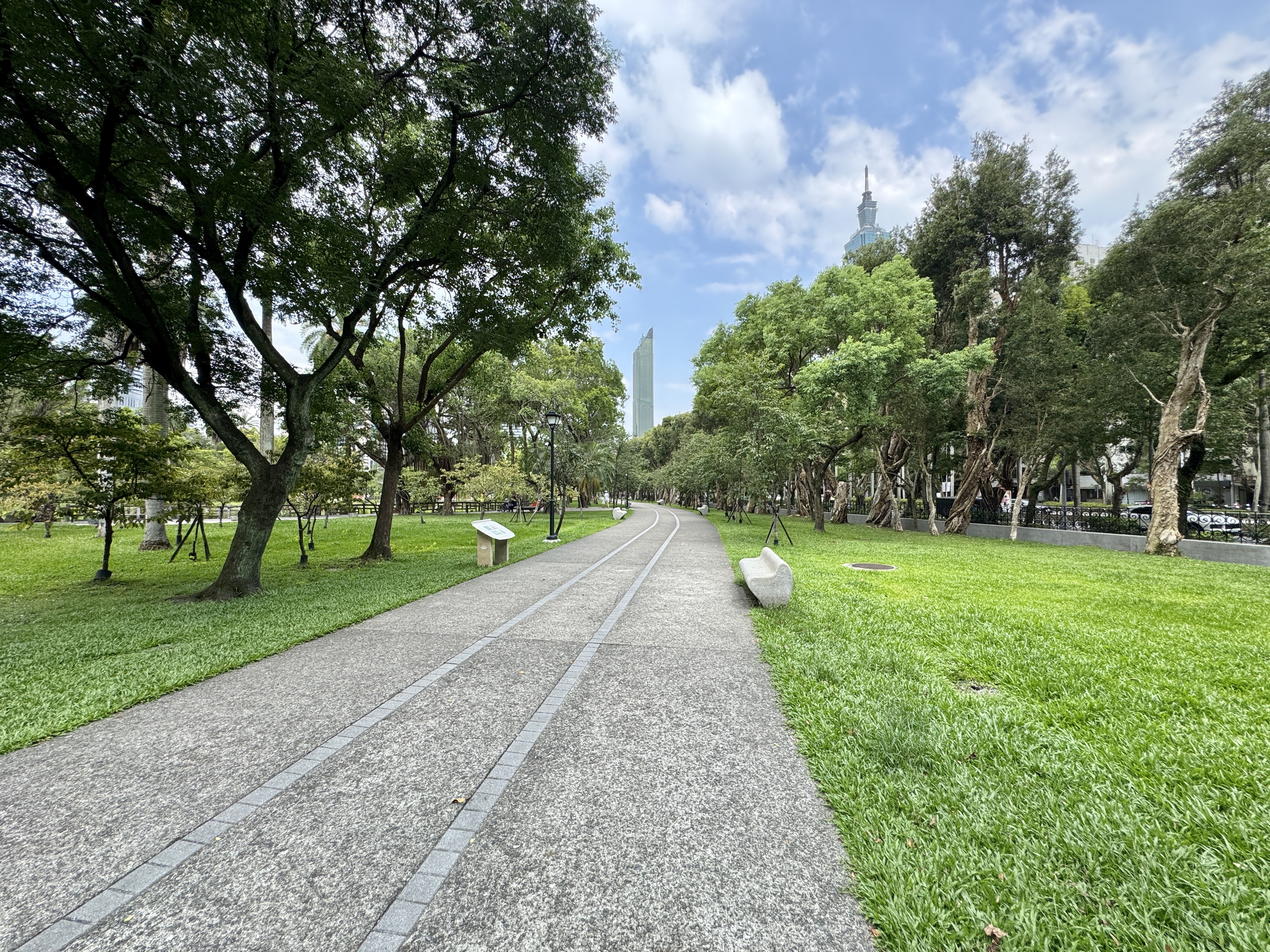 國父紀念館園區內的石板步道與大片草地，遠方可見樹木與天空。