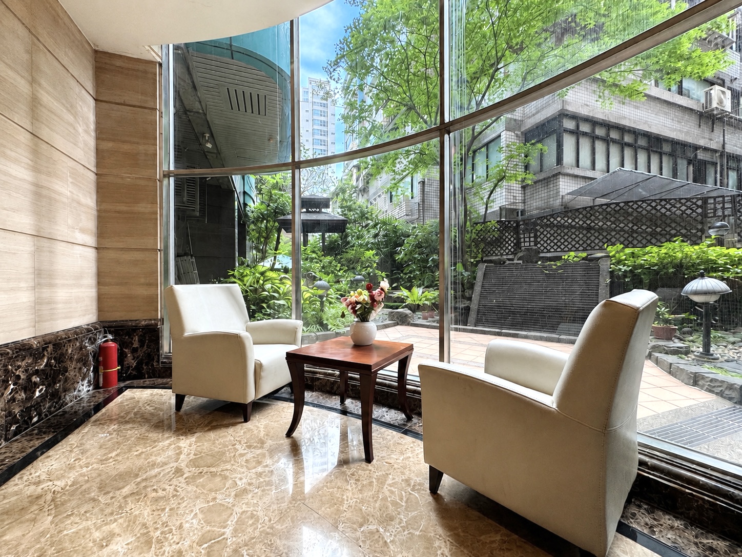 逸仙雅仕一樓大廳座位區，落地窗外可見社區公共花園。